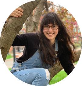 Amanda Pastore playfully posing for a picture in a tree on campus.